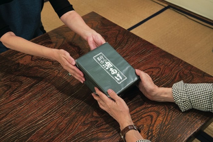 平松さんが差し出した包みの「栃尾名物油あげ」の文字が堂々と。長岡市栃尾地域の伝統の逸品。