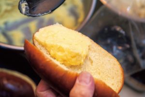 3. パンが冷めたら切り込みを入れ、カスタードクリームを下側に塗る。