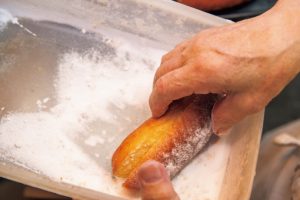 4. 砂糖（あればドーナツシュガー）をバットに入れ、パンにまぶしていく。