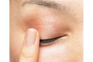 1. コーラルピンクを薬指に取り、手の甲などでなじませてから、アイホールよりひと回り広い範囲に大胆に、目頭から目尻にかけていれていく。これで気になるくすみも飛ぶ。