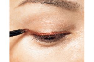 3. コッパーレッドを細筆に取り、筆の幅で、目頭から目尻へ大胆にラインを描く。メタリックな色は光の加減でうまい具合にエッジが飛んで見えるので、綿棒などでなじませなくても大丈夫。