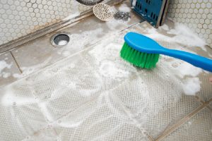 《11. 風呂掃除にピッタリな洗車ブラシを活用》毛先が細く、先割れ加工されている洗車ブラシ（ボディ用）は、浴槽の床の凹凸面に入り汚れをかき出す。トントン叩くようにアルカリ性洗剤を塗り広げてから磨く。