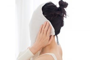 2.シートマスクの上から、蒸しタオルのパイル面をのせる。対角線上の端同士を持って耳まで覆うことで顔全体をしっかり温める。