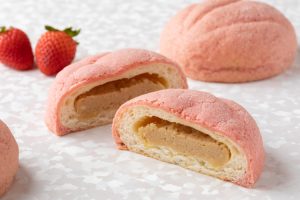 「いちごメロンパン」（280円／新作）苺の味がしっかりと感じられるピンク色のさくさくクッキー生地をまとったホテルメイドのメロンパン。中はアーモンドクリームと、クリームチーズを混ぜてほんのり酸味の効いたクリーム。