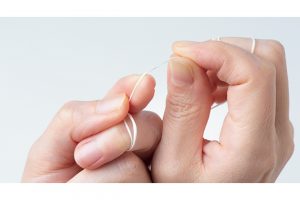 人差し指と親指で間をつまんで1〜2cmほどの長さにピンと張った状態で歯間に挿入する。