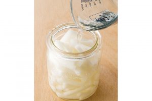 2.粗塩大さじ1と1/2〜2を３カップの水に溶かして塩水を作り、1のびんに注ぎ入れる。