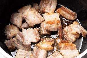 鍋に豚バラ肉を並べ、両面を弱めの中火で脂身が透き通るまでこんがりと焼きつける。