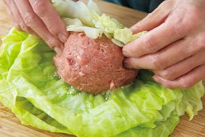 キャベツ4枚を重ね、まず手前の葉を一度肉だねに巻きつけ、右側の葉を内側に折る。再び手前からくるくる巻いて、最後に左側の葉を指で中に押し込む。巻き終わりを下にして鍋に入れる。