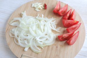 （1）玉ねぎ、にんにくは薄切りにする。トマトは8等分のくし形切りにする。赤唐辛子はヘタと種を取る。牛肉は塩・こしょう、酒をふっておく。
