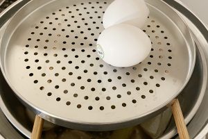 これは上で作った麻油鶏を保温しているときに、箸の上に付属のスチームプレートを置いて、一緒にゆで（蒸し）卵を作っているところ。