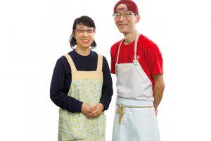 ＼ 「おいしいものを丁寧に作る」が モットーですよ！／滋さんと富美恵さんご夫婦。豆腐製造は滋さんが担い、揚げものや販売等を富美恵さんが担当する。