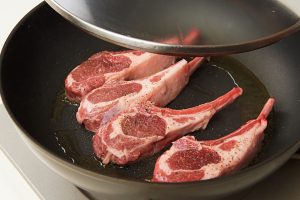 2.フライパンにオリーブ油を中強火で熱し、ラムチョップを並べてフタをする。【POINT】ラム肉は独特の匂いがあるので、香りのいいオリーブ油を使うことで中和する。