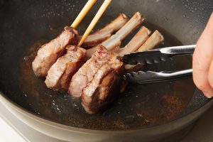 4.トングなどで肉を支えながら立て、側面の脂身がこんがりと色づくまで焼いて器に盛る。フライパンにトマトを入れて強火にかけ、断面が色づくまで焼き、肉に添える。