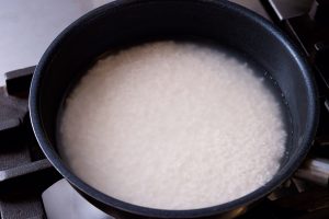 3.フライパンに洗い米を入れ、米と同じカップで水を計量する。米1カップに対し、水はカップ9分目。