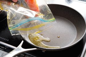 鮭を漬け、旨味が増したガーリックオイルを、袋からそのままフライパンへ。