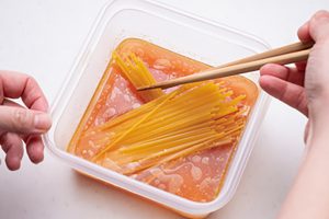 パスタは手で半分に折り、「×」にして入れ、箸で調味液になじませると麺がくっつかない。