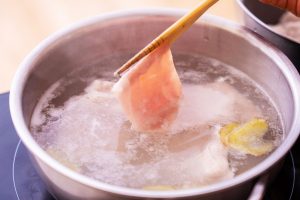 （2）鍋にたっぷりの湯を沸かし、しょうがを入れる。豚肉を熱湯にくぐらせ、色が変わったら湯を切る。