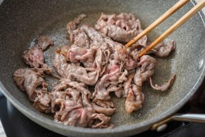 （4）フライパンに油（大さじ1）を中火で熱し、牛肉を炒める。