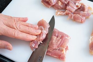 鶏肉を斜めに切って繊維を断ち切る。そぎ切りすることで肉の厚さも均一にできる。