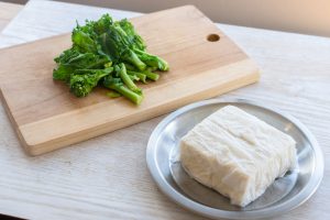 （1）豆腐は十字に切り、ペーパータオルで包んで15分ほど水気を切る。菜の花はさっと塩茹でし、2〜3等分に切る。しょうがはすりおろす。