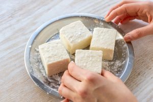 （2）豆腐の水気を拭き、塩を振り、片栗粉をまぶす。