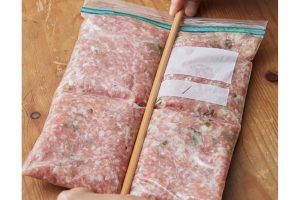 3.袋の上から手で肉だねを薄くのばし、平らにしながら徐徐に空気を抜き、口を閉じる。菜箸を押しつけて十字に筋をつけ、ラベルを貼ってバットにのせ、冷凍する。