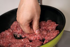 3.軽くこねた合いびき肉を団子状にしながらフライパンに並べ、押さえながら焼く。