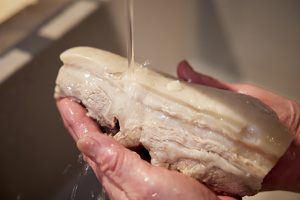 豚肉は下茹でした後、流水で洗うことで余分な脂が落ちてさっぱりする。崩れないようにそっと手で持って。