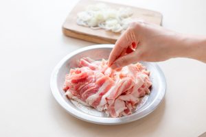 （1）長ネギは斜め薄切りにする。にんにくはつぶして芽を取る。豚バラ肉は4〜5cm幅に切り、塩・こしょうを振る。