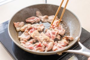 （3）香りが出てきたらにんにくを取り出し、豚肉を炒める。