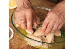 鶏の手羽中を、オリーブオイルとレモン汁でマリネードする北村さん。