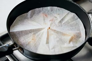 落とし蓋を使うと火の通りが早くなる。川津さんはクッキングペーパーで代用。