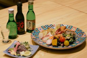 夕食のビュッフェで楽しむマイ皿鉢と、藁焼きカツオのたたき。料金は１人6,000円。高知の宴会に欠かせない日本酒も各種揃う。「日本３種 飲み比べ」3,000円