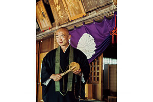 文化年間に再建された総欅造りの薬師堂で、湯杓を手に温泉寺の歴史を語る住職の小川祐章さん。薬師堂では湯治客が奉納した杖などを見ることができる