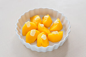 （2）耐熱皿に柿を並べ、ひと切れにつき小さじ1/3ほどのバターをのせる