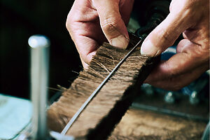 2. 折り曲げた針金に棕櫚を挟む。手先の微妙な感覚が大切となってくる