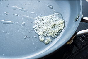 （2）同じフライパンに油とにんにくのみじん切りを入れて熱し、香りを出す