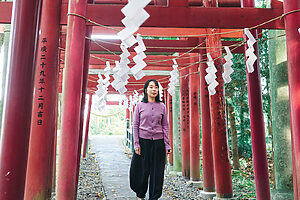 神社入り口から参拝者によって奉納された鳥居がたくさん並ぶ参道を歩く⾟酸なめ⼦さん。 樹林に囲まれた境内は、土と緑の匂いのする神聖な空気に包まれている