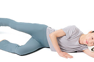 1. 左側を下に床に横になり、左手は丸めたタオルを枕にしながら頭を支え、右手は床に。左脚は膝を軽く曲げ、右脚はまっすぐに伸ばしつま先を床から少し浮かせる