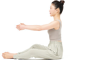 1. 両腕を伸ばして前に、脚は両膝をやや開いて伸ばし、床に座る。両膝を開くことで坐骨が立ちやすくなる