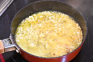 【茎アヒージョの作り方】鍋にサラダ油、にんにく、鷹の爪を入れて中火で熱する