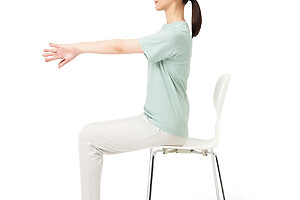 ❶椅子に浅く座り、地面と平行になるように両腕を前に伸ばし、手の甲を合わせる