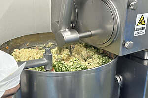 鍋に皮を剥いたじゃがいも、きゅうり、たまねぎ、セロリといった具材と調味料を投入、マシンでゆっくりと混ぜていく