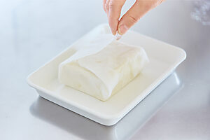 〈POINT〉豆腐を「リード クッキングペーパー」で包んで、半日以上水切りをする。吸収力が高いので、重しをのせなくてもOK。余分な水分を落とすと、調味がしやすくなる