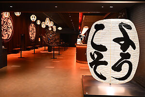 劇場に入ってすぐ左手には、「のれん中むら」による世界最大級のサイズの暖簾、そして、「小嶋商店」の巨大提灯がお出迎え