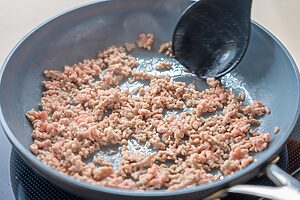 （2）フライパンにごま油を入れて中火で熱し、豚ひき肉を炒める