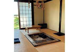 囲炉裏のある居間。縁側の先には緑豊かな畑が広がる