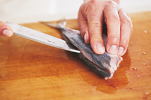 2. 腹を開いて内臓を出し、よく水洗いを。背側から包丁を入れ、骨に沿って引くように背骨まで身を切り開いたら、腹側からも包丁を入れて同様に