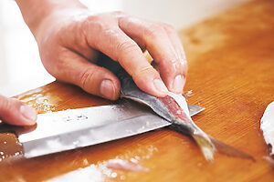 3. 尾側へスライドさせるように包丁を入れ、骨から身を完全に切り離す。さらに骨側を下に裏返して反対側も同様にすれば、三枚おろしが完了