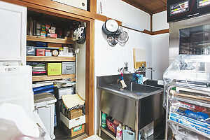 和室の押し入れに棚板を増設し、材料や梱包資材の収納に。鴨居にはフライパンなどをかけ、限られたスペースをむだなく活用している